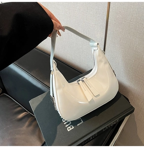 Détail du sac demi-lune en cuir verni blanc crème avec double fermeture éclair et argent
