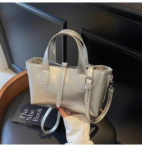 Detailed view of metallic silver bucket bag with buckle strap on a dark designer chair