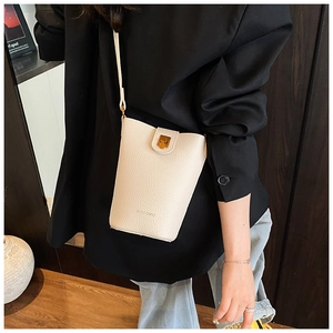 Detail einer cremefarbenen Lederbeuteltasche mit goldenem Drehverschluss am Gurt