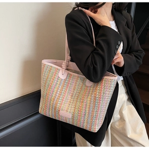 Detailed view of a woven tote bag with colorful stripes and pink handles worn by a model