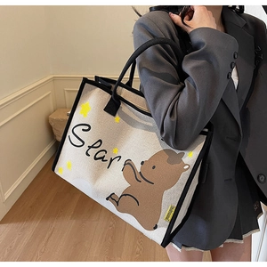 Détail du sac en toile avec illustration d'ours brun et poignées tressées noires