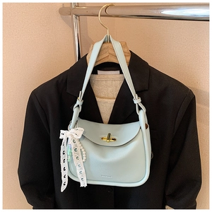 Detail of light blue crossbody bag with gold lock and lace pearl bow ornament