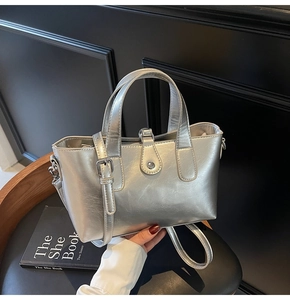 Detailed view of silver metallic leather tote bag with dual handles and square buckle strap