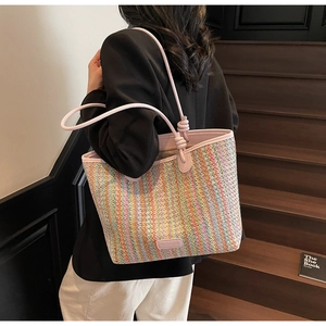 Detail of colorful striped woven tote bag featuring a pink leather strap and logo patch