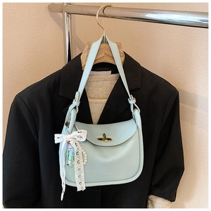 Close-up of light blue leather handbag with golden twist lock and lace bow charm detail