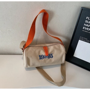 Détail du sac cylindre en toile rétro avec bandoulière tissée orange vif et broderie