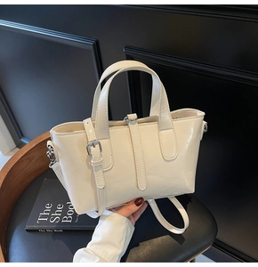 Detailed macro view of cream faux leather handbag with glossy finish and silver hardware