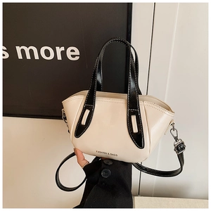 Detail of cream crossbody bag with black piping and Fashion & Bags text on the leather