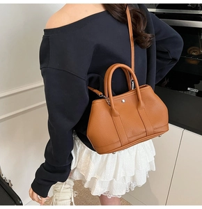 Detailansicht der braunen Bucket Bag aus Litschi-Leder mit Tragegriffen und Gurt