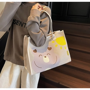 Détail d'un sac fourre-tout en toile avec ours violet et soleil sur un escalier