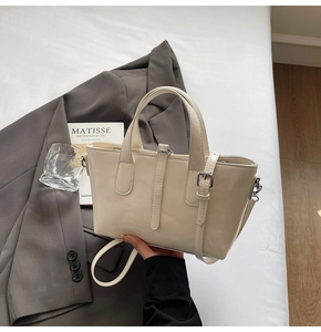 Beige faux leather tote bag detail with dual handles and adjustable shoulder strap
