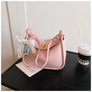 Detailed shot of a pink pebbled leather hobo bag with a gold clasp and lace bow