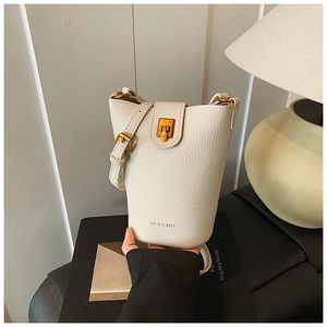 Detail der cremefarbenen Eimer-Tasche aus Lychee-Leder mit goldener Schließe