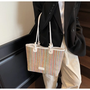 Macro view of a colorful woven straw tote bag featuring vibrant rainbow stripes and white logo