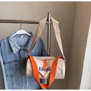 Vue détaillée du sac polochon en toile avec sangle orange et broderie 19 EST 85