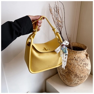 Detail of yellow lychee pattern leather bag with gold twist lock and lace bow decoration