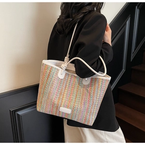 Detail of colorful striped woven tote bag featuring white leather straps and brand label