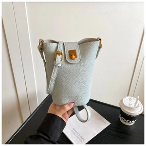 Detail einer hellblauen Bucket Bag aus Leder mit goldenen Elementen und Logoprägung