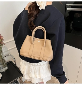 Detailansicht der beigen Eimer-Handtasche aus Leder mit Metallverschluss und Nieten