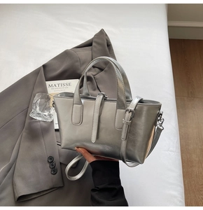 Detail of silver metallic tote bag with sleek top handles and detachable crossbody strap