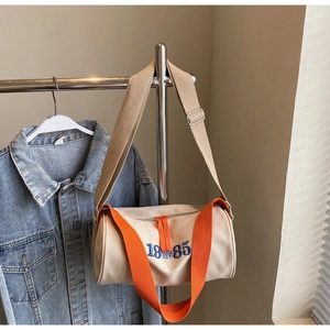 Détail du sac cylindre en toile avec bandoulière orange et broderie 19-85 EST
