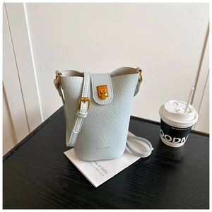 Detailaufnahme der hellblauen Eimertasche mit Lychee-Muster und goldenem Metallschloss