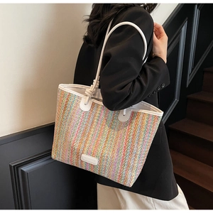 Detail of colorful woven stripes and white leather trim on a large shoulder tote bag