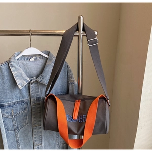 Détail du sac polochon en toile grise avec broderie 1985 EST bleue et bandoulières oranges