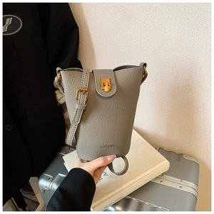 Detail der grauen Eimer-Tasche aus Leder mit goldener Schließe und HOCOMU-Logo