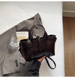Detail of dark brown glossy leather tote bag with silver hardware and shoulder strap