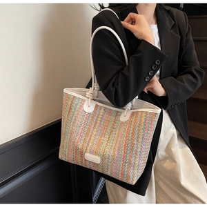 Close-up of colorful striped woven tote bag with white leather straps and brand plate