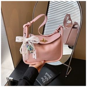 Detail of pink lychee leather handbag with pearl charm and lace bow decoration