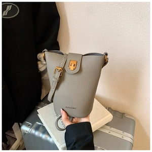 Detail einer grauen Eimer-Tasche aus Kieselleder mit Goldschließe im Lifestyle-Stil