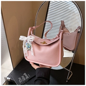 Detail of pink pebbled hobo bag featuring golden twist lock and white lace bow accessory