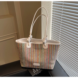 Detail of colorful striped woven tote bag with white shoulder straps and brand label