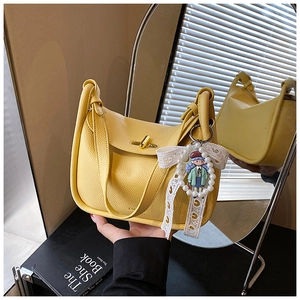 Detail der gelben Handtasche aus Leder mit goldenem Schloss und Perlenanhänger