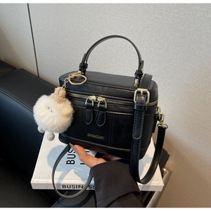 Détail d'un sac boîte noir avec fermetures dorées et pendentif ours en peluche