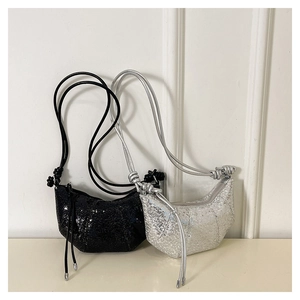 Detail of sequin half-moon bags in black and silver featuring knotted shoulder straps