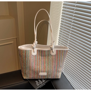 Detail of colorful woven tote bag featuring vibrant stripes and YUEMANDI leather logo tag