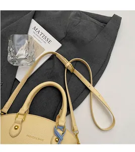 Detail of lychee pattern beige shell bag with fashion brand logo and smooth shoulder strap