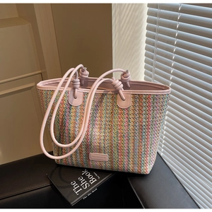 Detail of colorful woven tote bag featuring striped texture and pink knot strap detail