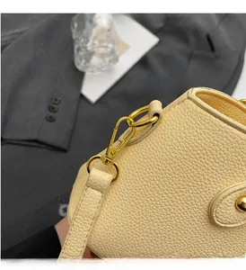 Detailed close-up of yellow pebble grain leather and shiny gold metal hardware on handbag