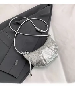 Detail of silver sequined croissant bag with knotted shoulder strap and metallic shimmer
