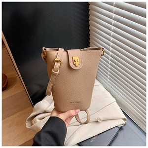 Detail der aprikosenfarbenen Eimer-Tasche aus genarbtem Leder mit Goldverschluss