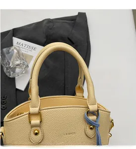 Detail of beige bucket bag featuring lychee grain leather and gold metal hardware