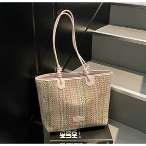 Detail of colorful striped woven tote bag featuring light pink leather handles and knot design