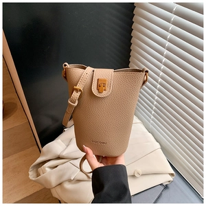 Detail der beigen Beuteltasche mit Litschi-Muster, verstellbarem Gurt und Goldverschluss