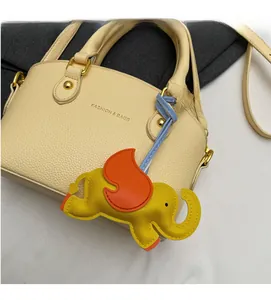 Detail of cream bucket bag with litchi texture and elephant charm on gray background