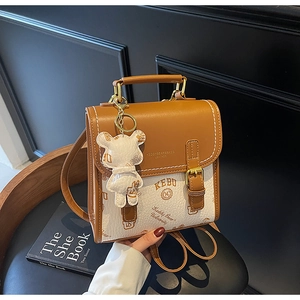 Detail eines Vintage-Rucksacks in Braun und Weiß mit einem 3D-Lederbären-Anhänger