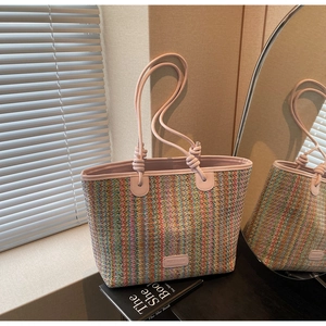 Detail of colorful striped woven tote bag with pink leather edges and branded logo patch